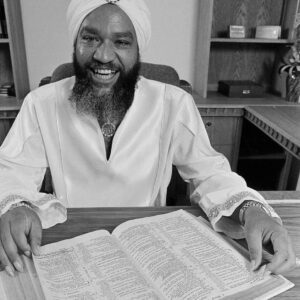 A man in a turban sitting at a desk with an open book, showcasing Ongoing Training.